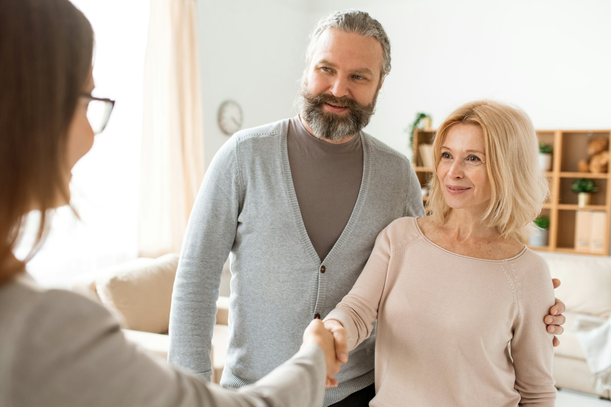 Happy mature couple welcoming their real estate agent at home